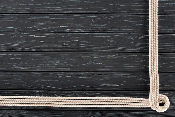 bovenaanzicht van gearrangeerde witte mariene touwen op donkere houten tafelblad - Foto, afbeelding