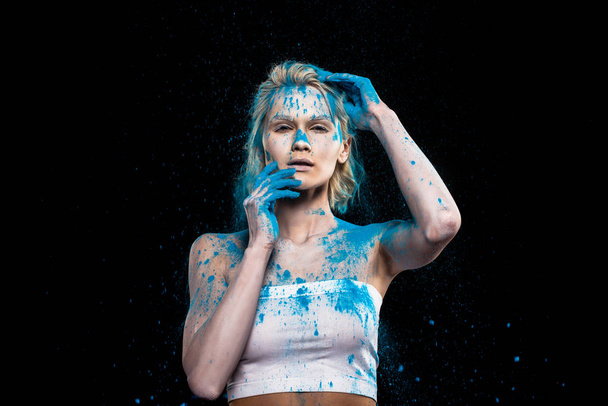 young sensual woman posing in blue powder paint, isolated on black - Photo, Image