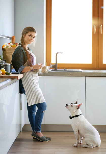 Portrait of young woman standing against kitchen background. - Foto, afbeelding