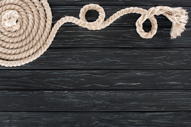 vista superior de cuerda marina blanca dispuesta en círculo sobre mesa de madera oscura
 - Foto, Imagen