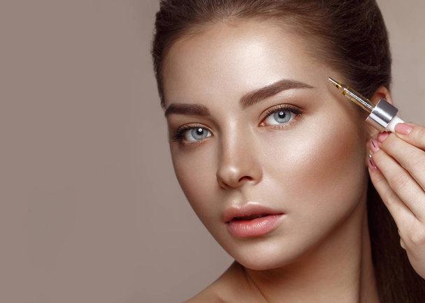 Beautiful young girl with natural nude make-up with cosmetic in hands. Beauty face. - Foto, Imagem