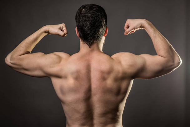 Handsome muscular bodybuilder on gray background, rear view. - Φωτογραφία, εικόνα