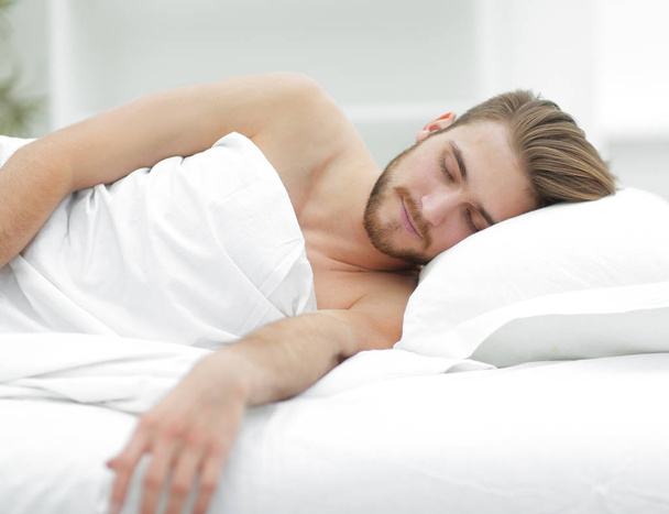 smiling man sleeping on a comfortable bed. - Foto, Imagen