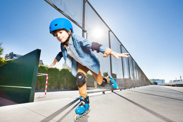 Preteen boy in roller blades and protective wear doing tricks with his hands like wings - Φωτογραφία, εικόνα