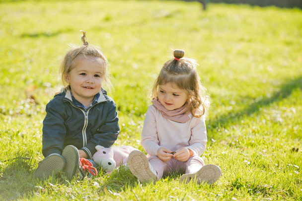 Dzieci bawiące się na zielonej trawie na słoneczny dzień. Szczęśliwa rodzina, dzieciństwo, miłość, zaufanie koncepcja. Dzieci, przyjaciele, przyjaźń. - Zdjęcie, obraz