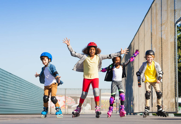 Happy inline skaters, preteen boys and girls, having fun at stadium outdoors - Фото, изображение