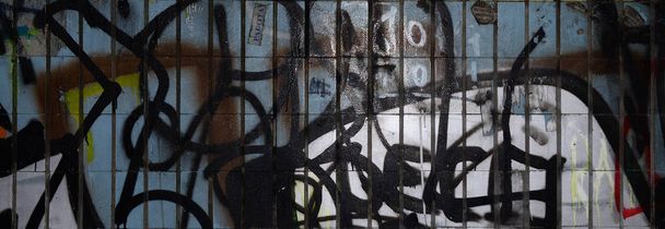 Um fragmento de graffiti desenho e um conjunto de etiquetas aplicadas à parede a partir da telha velha no túnel do metrô. O conceito de arte de rua e vandalismo
 - Foto, Imagem
