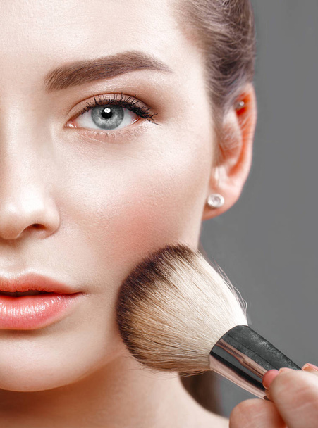 Beautiful young girl with natural nude make-up with cosmetic tools in hands. Beauty face. - Foto, imagen