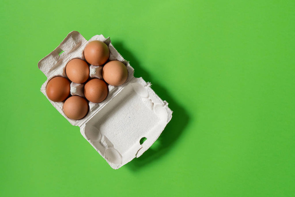 Huevos de pollo en envases de papel ecológico sobre un fondo verde
. - Foto, imagen