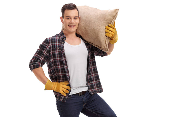 Farmer holding a burlap sack and looking at the camera isolated on white background - Фото, изображение