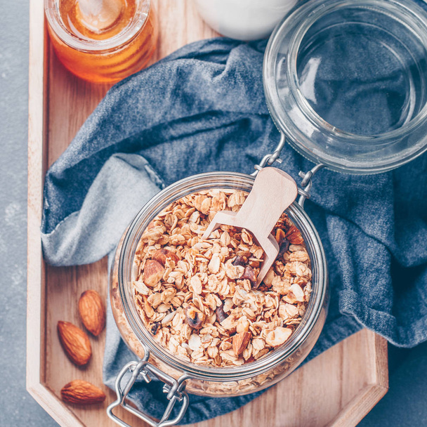 Healthy Breakfast - Granola, milk or yogurt and honey on wooden tray on stone table background. Top view, close up - Photo, image