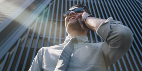 casual male using phone near modern building and enjoying sunny day. - Felvétel, videó