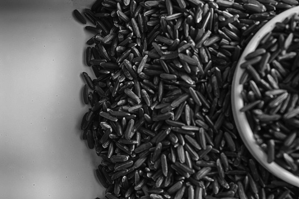 Monochroom Jasmine bruine volkoren rijst in kleine plaat het concept van goede voeding en een gezonde levensstijl. Bovenaanzicht, close-up als achtergrond of textuur - Foto, afbeelding