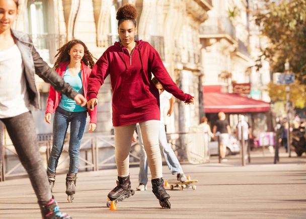African teenage girl roller skating around the cones at city side walk - Fotó, kép