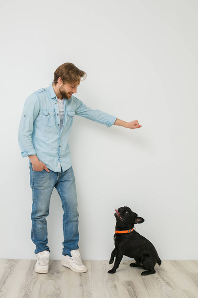 young blonde guy, handsome man, playing and loving his dog, on white background - Foto, Bild