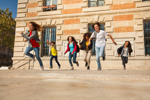 Щасливі хлопчики і дівчатка-підлітки, що біжать з будівлі коледжу після занять
 - Фото, зображення