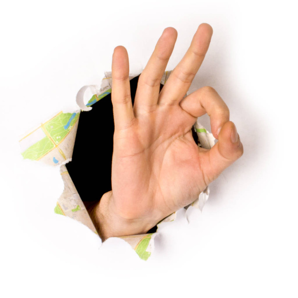 primer plano de la mano femenina que sale de un agujero en un papel, signo bien, aislado en blanco
 - Foto, Imagen