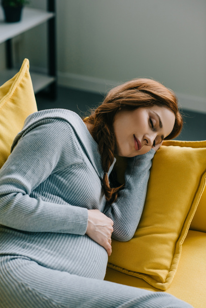 attractive pregnant woman sleeping on sofa in living room - Φωτογραφία, εικόνα