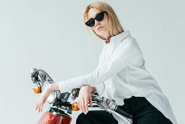 Attractive young woman in sunglasses on vintage scooter isolated on grey - Zdjęcie, obraz