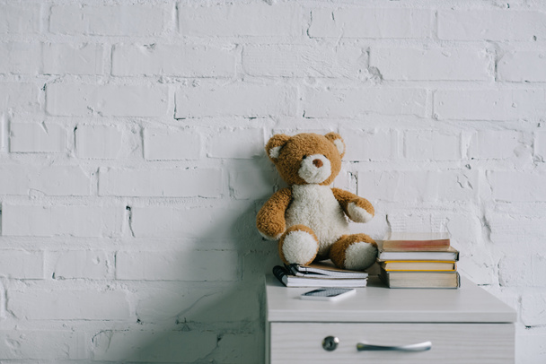 teddy bear, copybooks and books on wooden side table - Zdjęcie, obraz