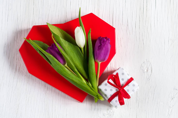 Hermosos tulipanes en un corazón rojo. Fondo de madera blanca. Día de la Madre. Feliz Día de la Mujer
. - Foto, imagen