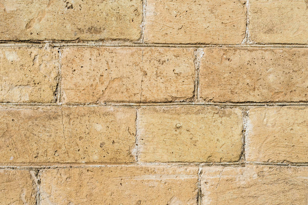 Close-up Textured background of a stone brick of yellow antediluvian masonry. Partially destroyed wall. Brick grunge background in vintage style - Valokuva, kuva