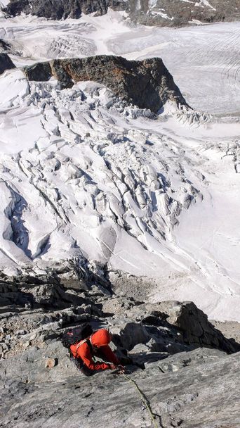 bir buzulun üzerinde yüksek bir maruz tırmanma yolu üzerinde erkek dağcı - Fotoğraf, Görsel
