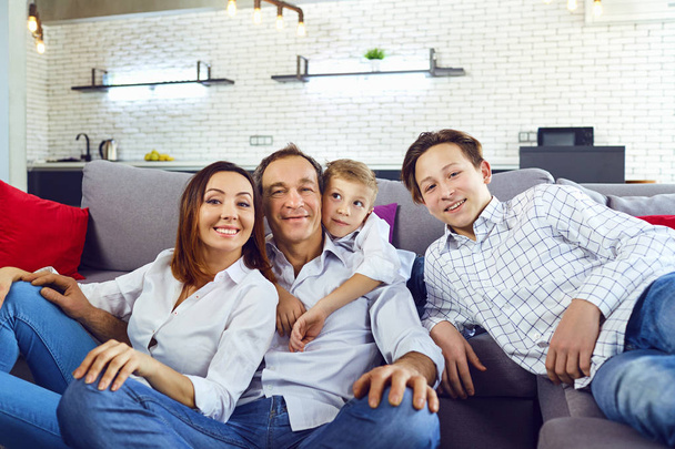 Happy family smiling sitting on sofa in room. - Foto, afbeelding