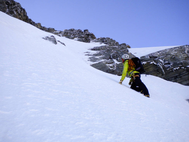 mężczyzna przewodnikiem, wspinaczka couloir stromym śniegu na drogę na szczyt w Alpach Szwajcarskich - Zdjęcie, obraz
