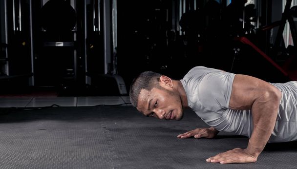 Asiaten trainieren mit Liegestützen auf dem Boden in modernen Fitnessstudios. - Foto, Bild