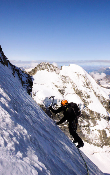 männlicher Bergsteiger auf einem hochalpinen Gletscher mit toller Aussicht auf die fantastische Berglandschaft hinter sich - Foto, Bild
