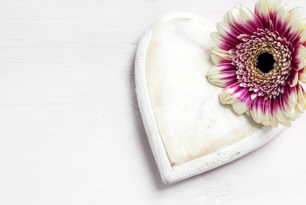wooden heart and a flower on a white painted background, love symbol for valentines or mothers day, copy space - Photo, Image