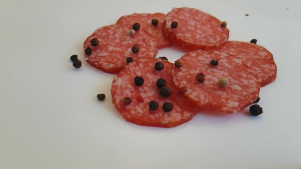 Wurst Salami Tropfen schwarzer Pfeffer auf weißem Hintergrund Zeitlupe - Filmmaterial, Video