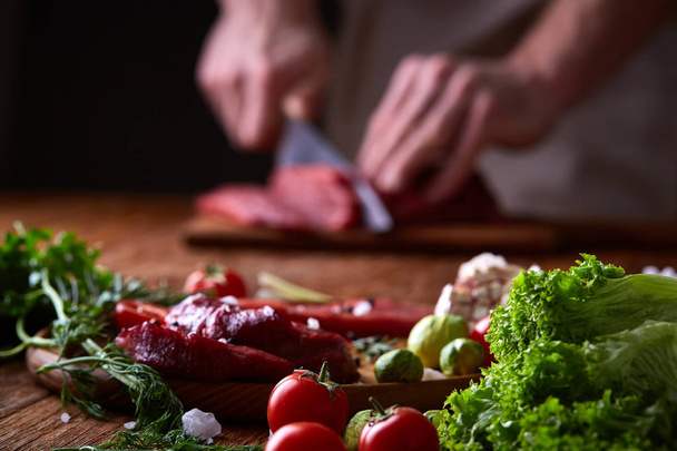 Strong professional mans hands cutting raw beefsteak, selective focus, close-up - Foto, immagini