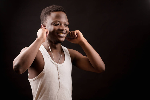 handsome smiling Afro man putting on earphones.music fan.have a rest. - Foto, Imagen