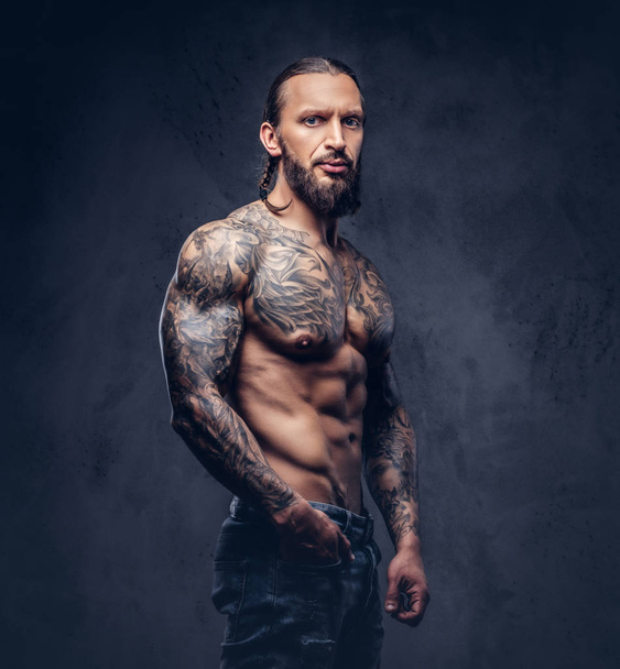 スタイリッシュなヘアカット、暗い背景上に孤立と筋肉裸髭 tattoed 男性のクローズ アップの肖像画. - 写真・画像