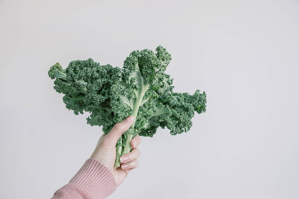 holding green kale leaves in hand - Foto, afbeelding