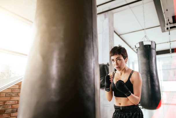 kung fu girl practising karate with boxing bag at sport hall - 写真・画像
