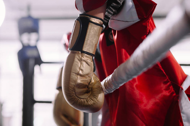 beaten boxer in yellow boxing gloves leaning on ropes - Φωτογραφία, εικόνα