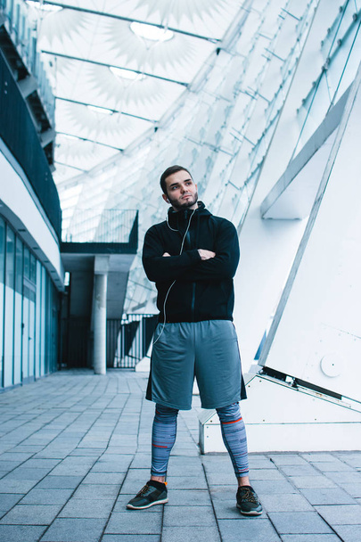 Confidant and healthy. Full length of young man in sportswear standing against industrial city view - 写真・画像