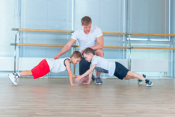 Group of children doing kids gymnastics in gym with teacher. Happy sporty children in gym. bar exercise. plank. - Foto, imagen