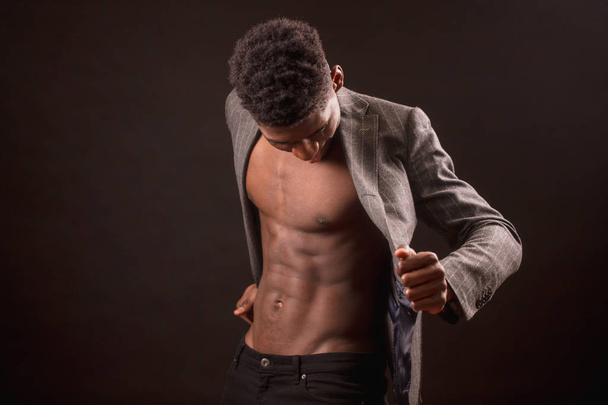 black man with naked body is looking for money on his inset pockets of jacket - Fotó, kép