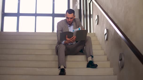 businessman with folder sitting on stairs - Filmati, video