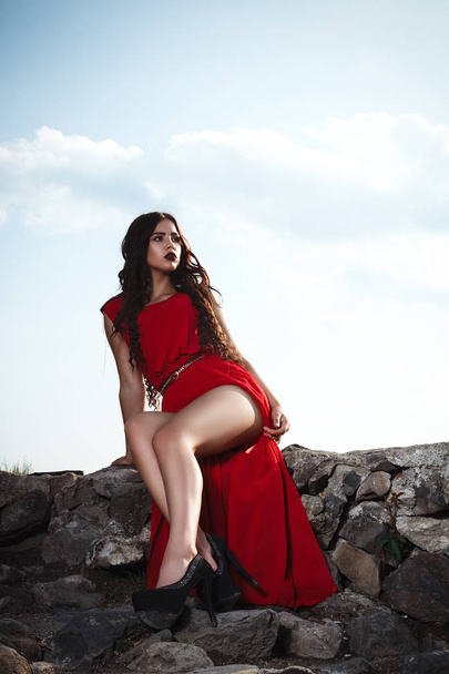 Seksikäs tyttö punainen mekko poseeraa vanha rock linna pitkät jalat
  - Valokuva, kuva