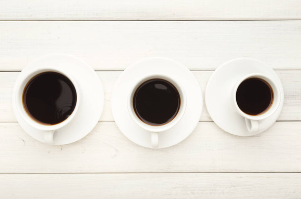 Various cups with black coffee on white wooden table - Photo, Image