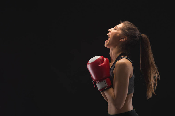 Side view of emotional young woman with boxing gloves - Photo, image