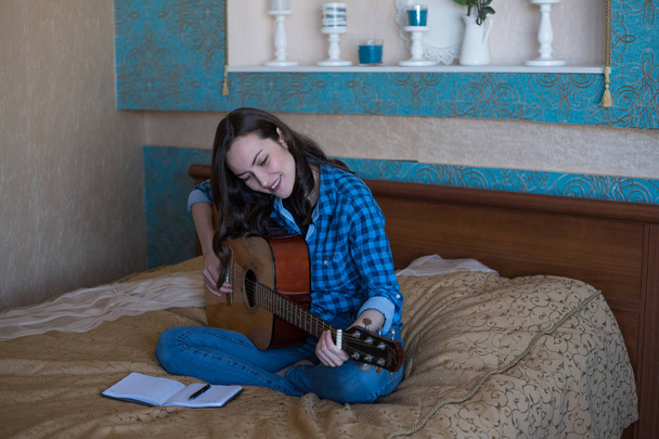 Φυσικό πορτρέτο ενός νεαρού κοριτσιού, να μάθουν να παίζουν ακουστική κιθάρα. η έννοια της δημιουργικότητας - Φωτογραφία, εικόνα