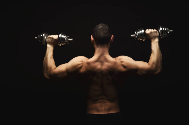 starker athletischer Mann mit Hantel zeigt nackten muskulösen Körper - Foto, Bild