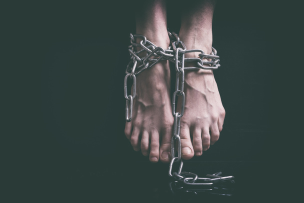 Exhausted female feet with swollen veins associated hanging metal chains closeup over black background, toned in retro film - Fotoğraf, Görsel