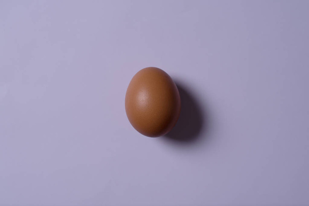 Minimalismo. un huevo en la imagen central sobre un fondo ultravioleta
. - Foto, imagen